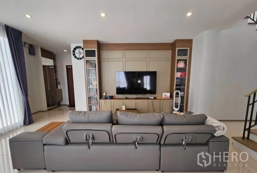 บ้านเดี่ยว for rent or sale in Lat Krabang, Bangkok - ห้องนั่งเล่นโล่งโปร่ง โซฟาตัวยาวหันเข้าผนังทีวีบิลท์อิน