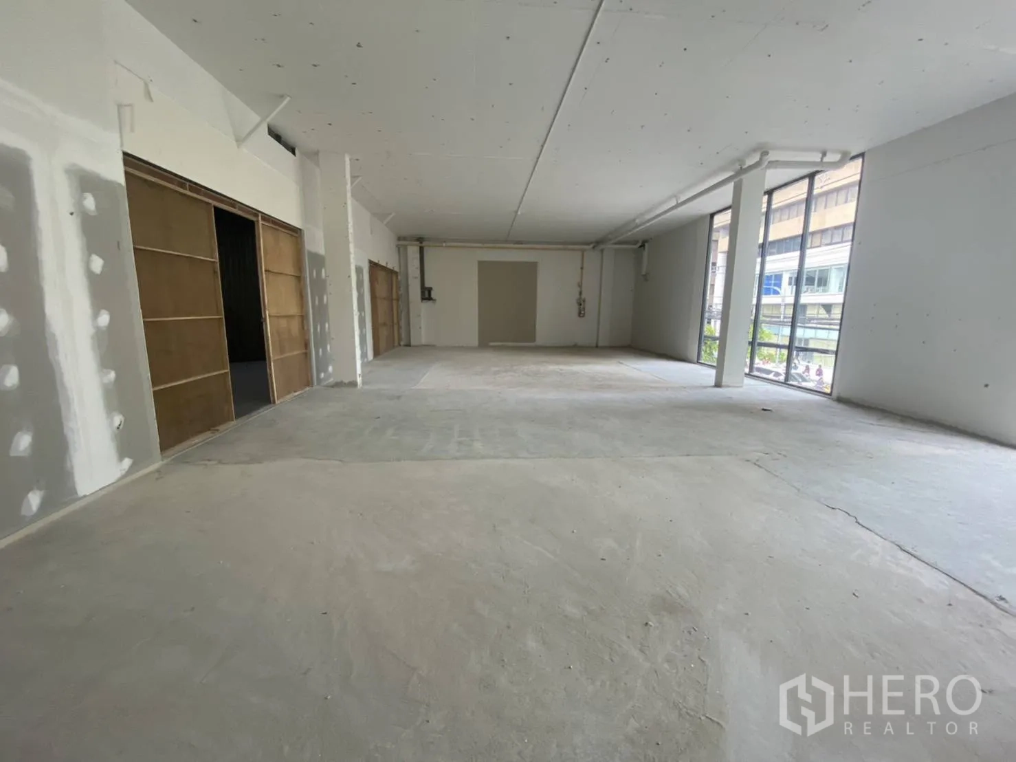 พื้นที่ขายปลีก ให้เช่า - ภายในสว่าง ผนังยังไม่ตกแต่ง ด้านหน้ากว้าง มีกระจกสูงมองเห็นวิวเมือง พร้อมสำหรับปรับตกแต่งตามแบรนด์