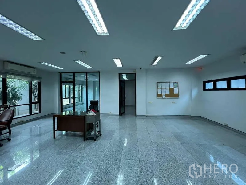 Office Space for sale in Bang Na, Bangkok - Large workspace with fluorescent lighting, desk and garden-facing windows.
