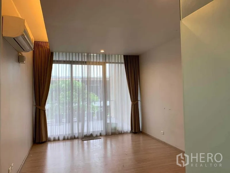 联排别墅 出租在Khan Na Yao, Bangkok - 木地板卧室，带空调，落地玻璃门通向阳台与窗帘。