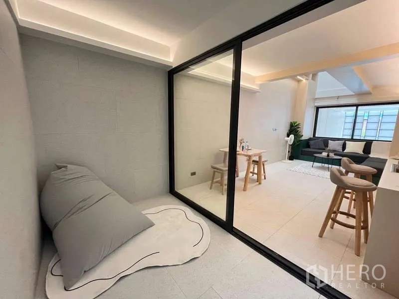Townhouse for sale in Khlong Toei, Bangkok - Glass-partitioned nook with floor cushion overlooking the living space.