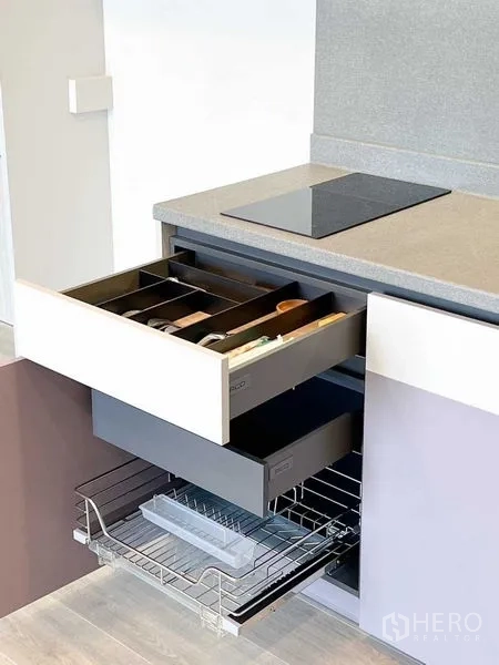 Condominium for rent or sale - Modern kitchenette with induction hob and open drawers showing utensil organizers and pull-out wire racks.