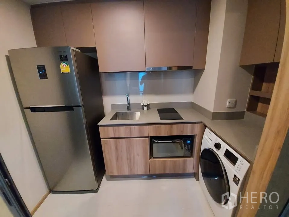 Condominium for rent in Watthana, Bangkok - Compact enclosed kitchen with fridge, hob, sink, microwave and washer-dryer.