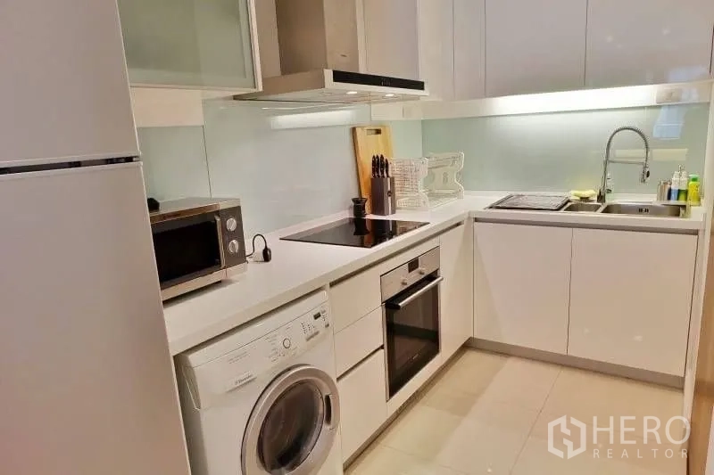 คอนโด ให้เช่าในKhlong Toei, Bangkok - ครัวรูปตัว L สมัยใหม่ พร้อมเตาอบ เตาไฟฟ้า เครื่องดูดควัน อ่างล้างจาน และเครื่องซักผ้า