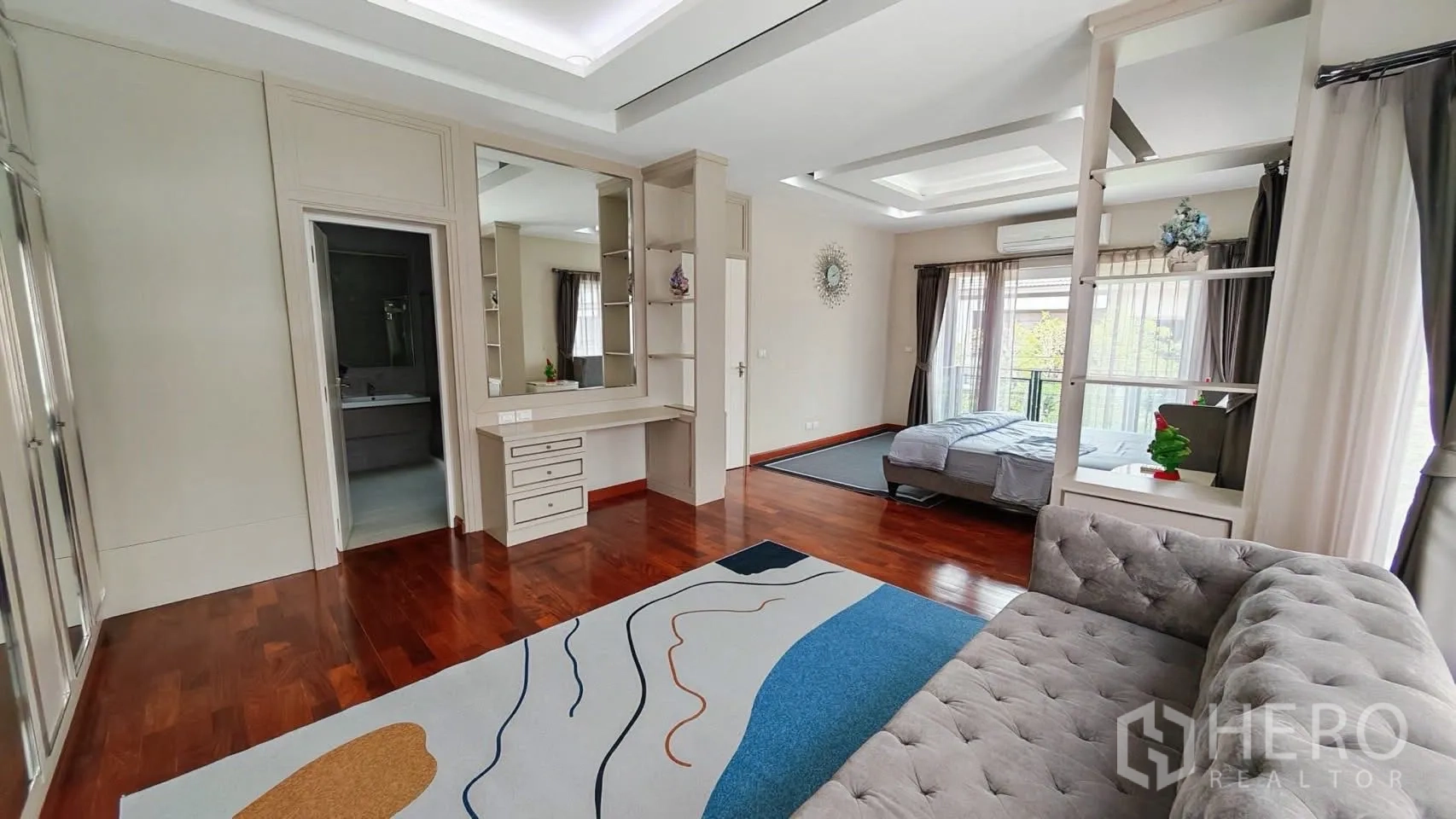 Detached House for rent or sale in Bang Phli, Samut Prakan - Spacious suite with sofa, vanity, and doorway to the ensuite beside the sleeping area.