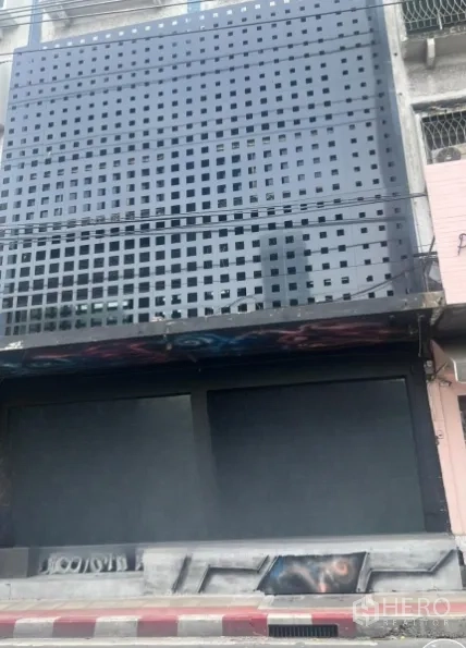 อาคารพาณิชย์ ให้เช่าในWatthana, Bangkok - ด้านหน้าอาคารพาณิชย์ติดถนน มีแผงโลหะเจาะรูสีดำและประตูม้วนปิด