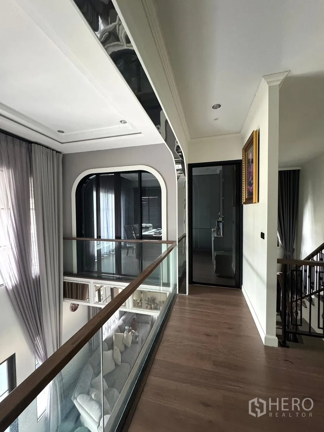 独立式住宅 出售在Mueang Pathum Thani, Pathum Thani - 二层走道，玻璃栏杆俯瞰客厅。