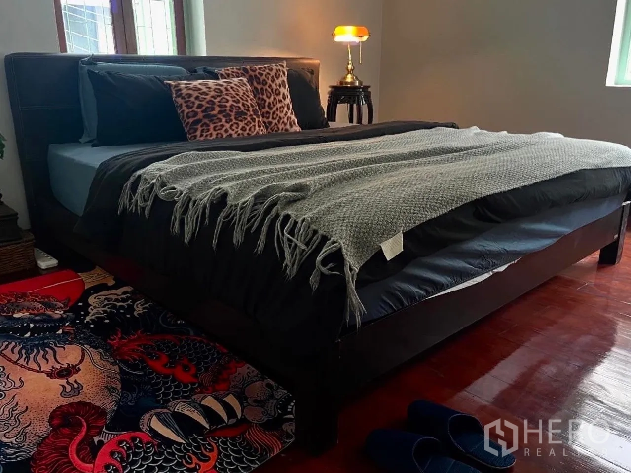 Shophouse for rent in Bang Rak, Bangkok - Bedroom with dark bedframe, patterned rug, and throw blanket.