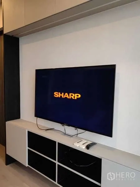 Condominium for rent in Watthana, Bangkok - Wall-mounted flat-screen TV above a built-in media cabinet and shelving in a modern condo.