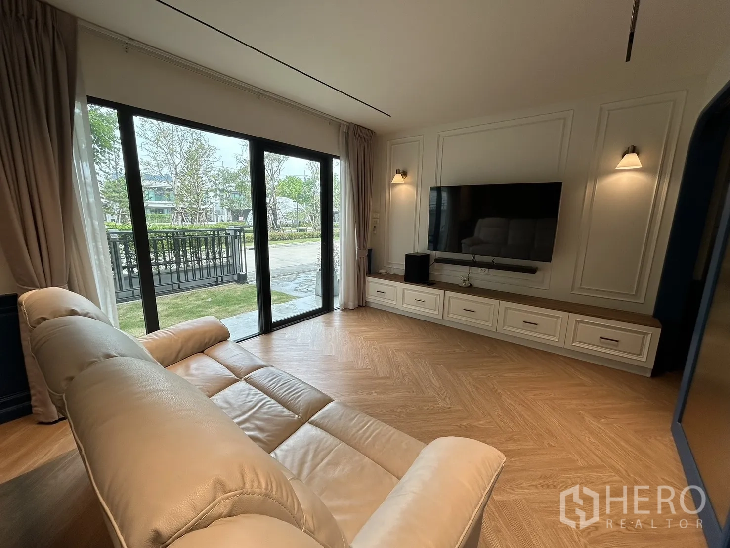 Detached House for rent in Bang Phli, Samut Prakan - Cozy lounge with sofa facing TV and large windows to the yard.