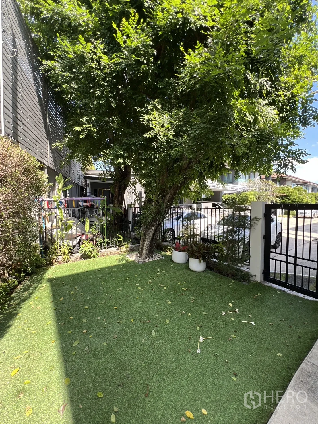 独立式住宅 出售在Bang Kapi, Bangkok - 树荫草坪，花盆与前门栅栏。