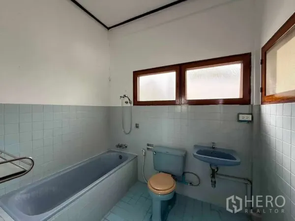 独立式住宅 出租在Watthana, Bangkok - 复古风浴室，带蓝色浴缸、马桶和带磨砂玻璃的窗户。