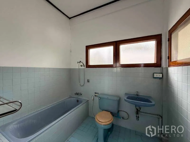 独立式住宅 出租在Watthana, Bangkok - 复古风浴室，带蓝色浴缸、马桶和带磨砂玻璃的窗户。