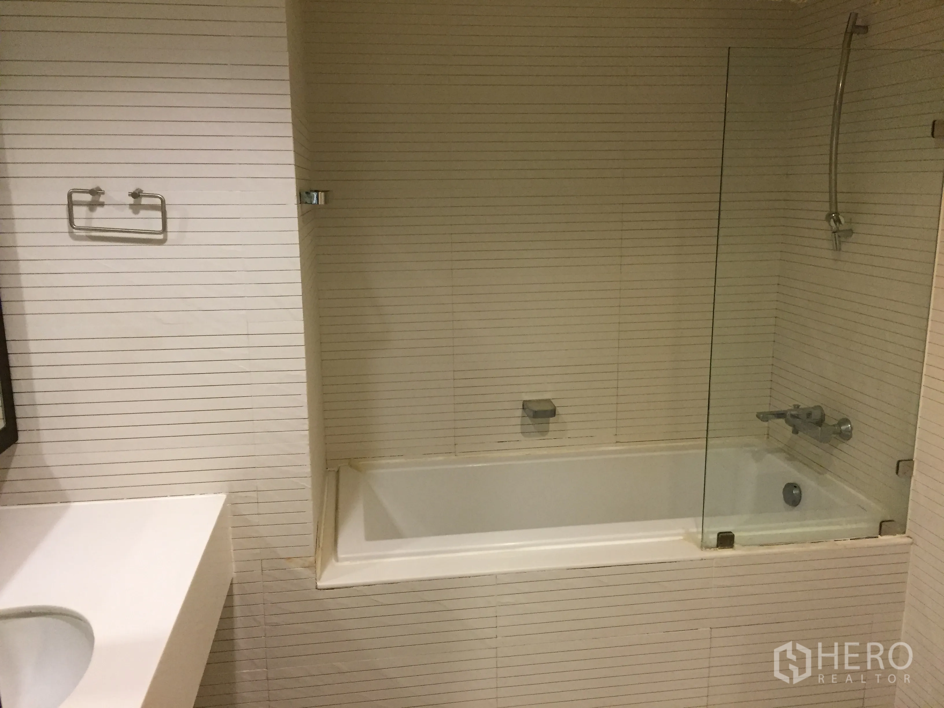 Condominium for rent in Watthana, Bangkok - Bathroom with bathtub, glass shower screen and white tile walls.
