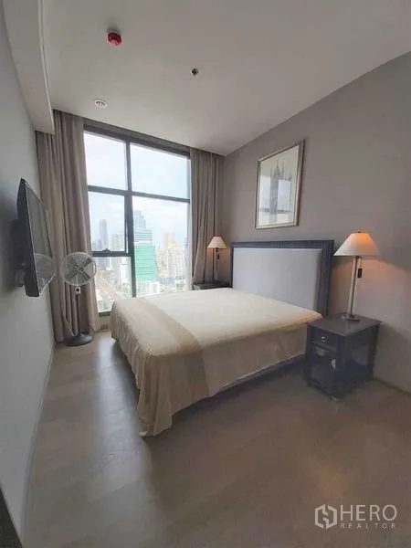Condominium for sale in Bang Rak, Bangkok - Bedroom with floor-to-ceiling window offering Bangkok skyline views, queen bed, and soft lighting.