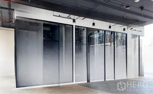 Retail Space for rent - Wide glass storefront with black frames, track lighting, and a polished concrete floor.