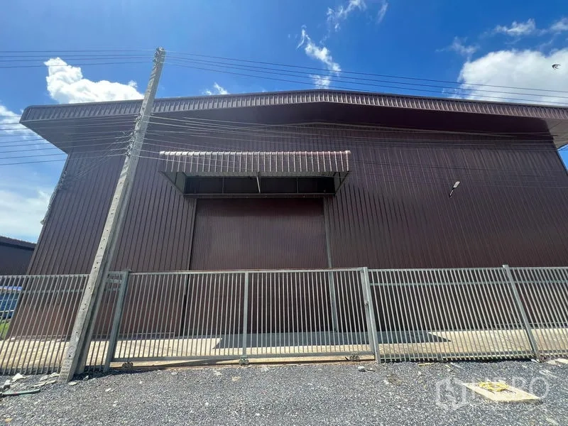 คลังสินค้า ให้เช่าในMin Buri, Bangkok - ด้านหน้าตัวอาคารมีประตูม้วนขนาดใหญ่ ชายคากันฝน และรั้วเหล็กด้านหน้า