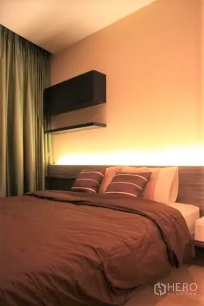 Condominium for rent in Watthana, Bangkok - Cozy bedroom with double bed, warm backlit headboard, dark curtains and wall shelves.