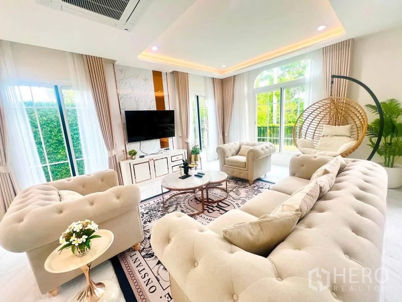 Detached House for rent in Bang Phli, Samut Prakan - Elegant living room with tufted sofas, TV wall, large windows, and a hanging chair.