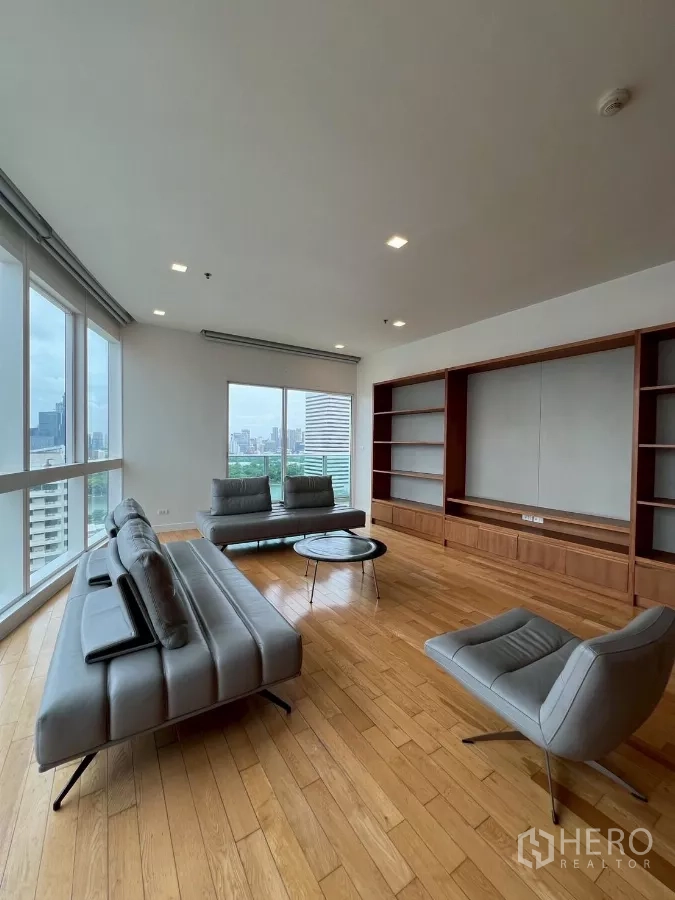 公寓 出租在Khlong Toei, Bangkok - 开放式起居区，城景视野，灰色沙发组与圆形茶几，整面书架。