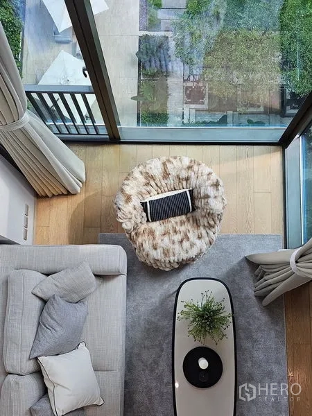 Condominium for rent - Top-down shot of lounge with rug, coffee table, and glass wall overlooking greenery.