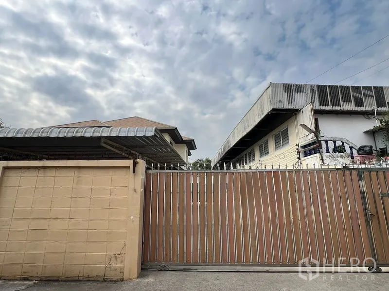 บ้าน ให้เช่าหรือขายในLak Si, Bangkok - ด้านหน้าบ้าน ประตูเลื่อนโลหะกว้างและกันสาดโรงรถ โดยมีตัวบ้านสองชั้นอยู่ด้านใน