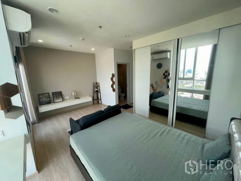 Condominium for rent in Huai Khwang, Bangkok - Master bedroom angle showing mirrored wardrobe and doorway to bathroom.