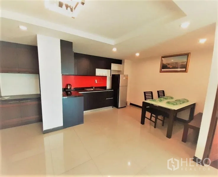 คอนโด ให้เช่าในWatthana, Bangkok - ครัวบิวท์อินโทนเข้มพร้อมผนังกระจกกันเปื้อนสีแดง โต๊ะทานข้าวและตู้เย็น