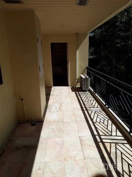 Condominium for sale - Sunny balcony with tiled flooring and metal railing facing trees.