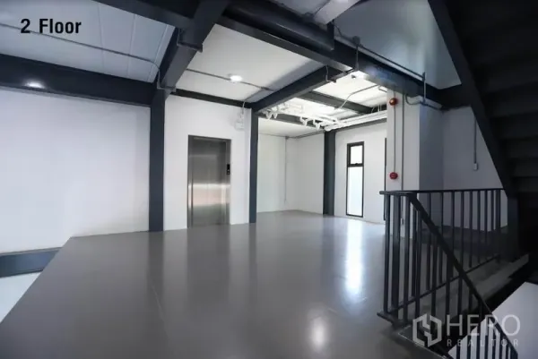 Warehouse for rent in Wang Thonglang, Bangkok - Second-floor landing with elevator, windows and industrial-style staircase.