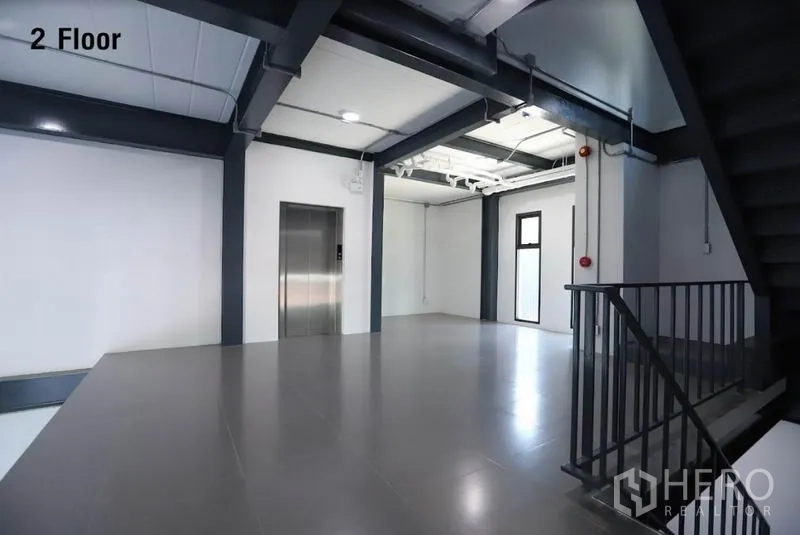 Warehouse for rent in Wang Thonglang, Bangkok - Second-floor landing with elevator, windows and industrial-style staircase.