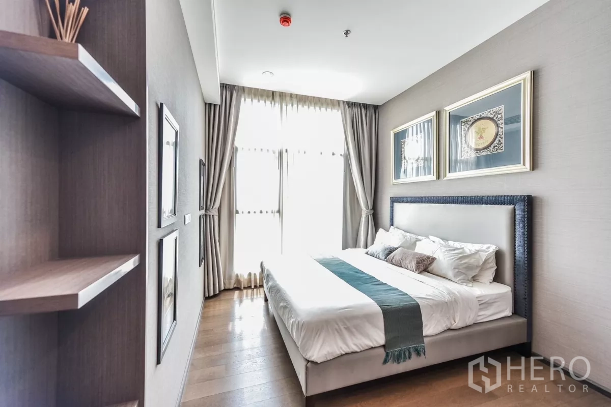 公寓 出租或出售在Bang Rak, Bangkok - 宽敞卧室，面向高窗，墙面置物架与柔和中性色调。