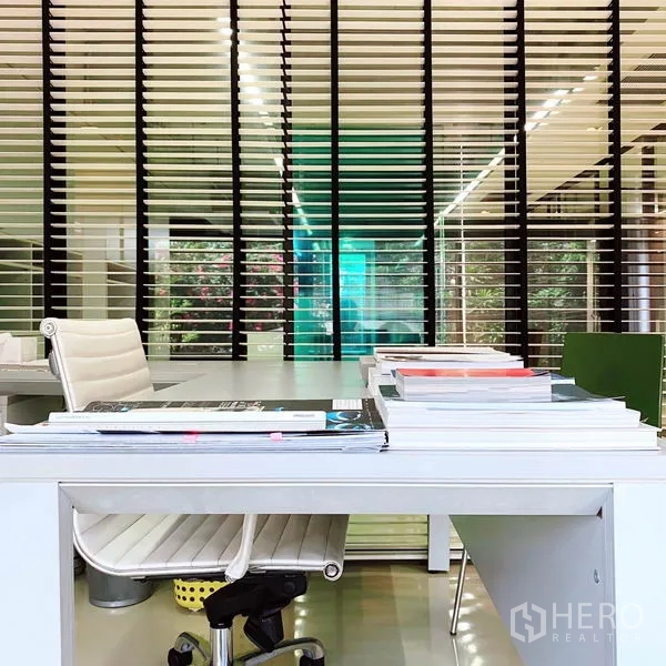 สำนักงาน ให้เช่าในPhaya Thai, Bangkok - โต๊ะทำงานสีขาวพร้อมเก้าอี้ มองไปยังบานเกล็ดแบบแนวตั้งและผนังกระจกสีฟ้าเขียว