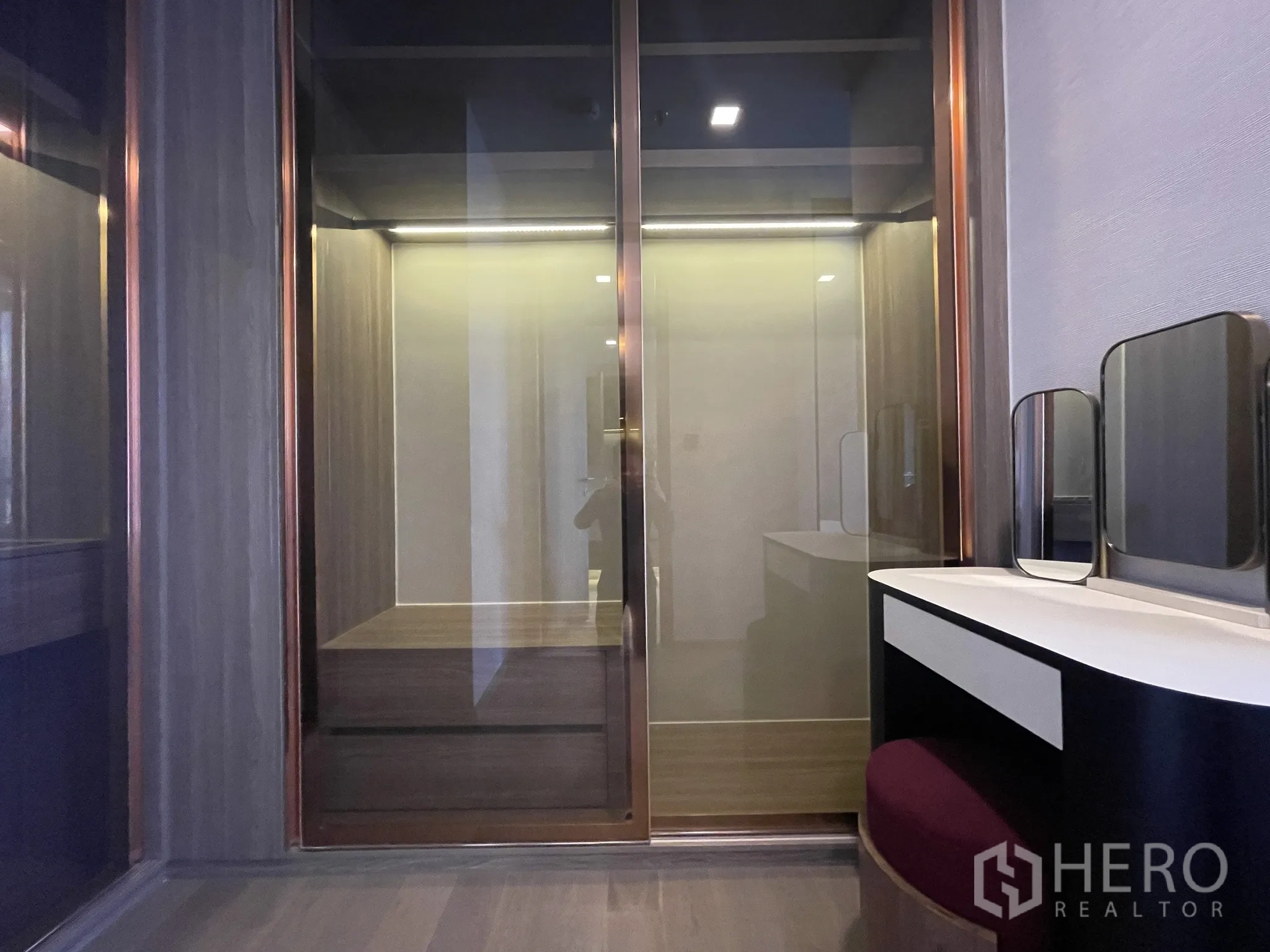 Condominium for rent in Watthana, Bangkok - Walk-in closet with glass-front wardrobes and a vanity desk.