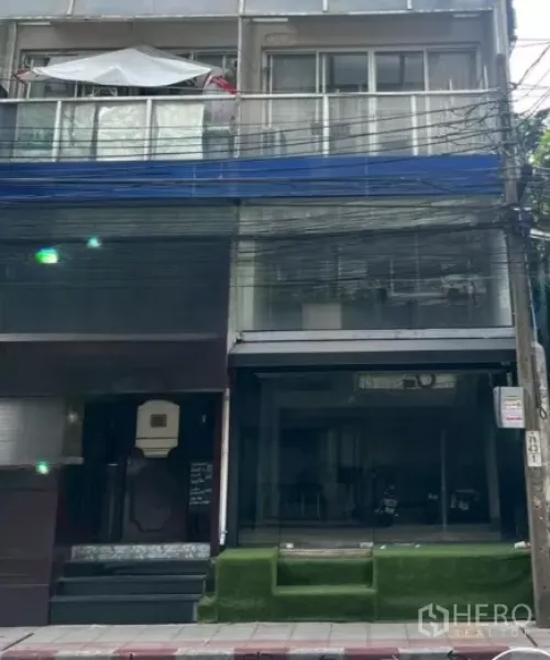 零售空间 出租在Watthana, Bangkok - 临街商住楼外观，落地玻璃店面与草坪台阶。