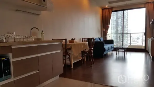 公寓 出租在Sathon, Bangkok - 开放式客厅与小厨房、餐桌、蓝色沙发，阳台可眺望沙吞天际线