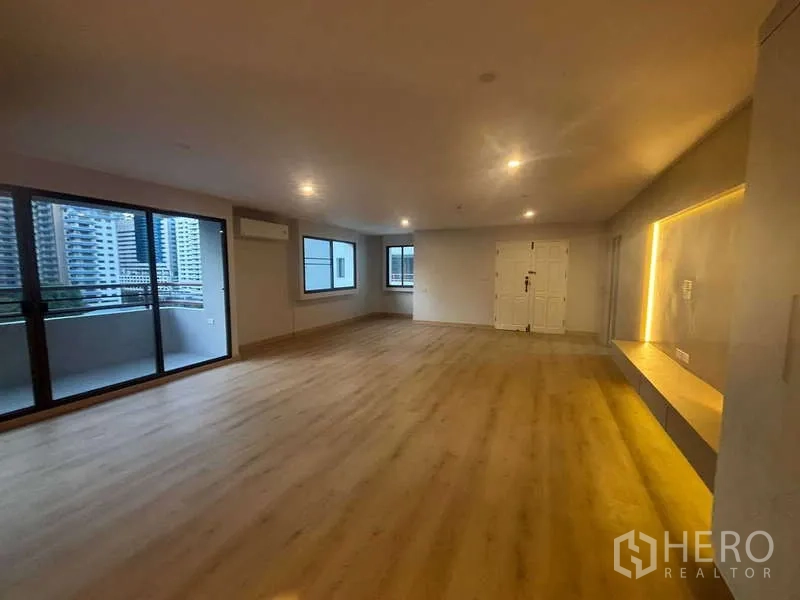 คอนโด ขาย - ห้องนั่งเล่นกว้าง มองเห็นระเบียง มีหน้าต่างหลายบานและพื้นไม้