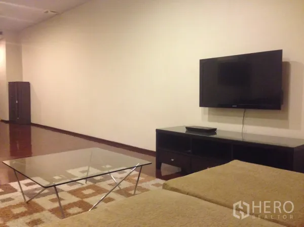 คอนโด ให้เช่าในWatthana, Bangkok - ห้องนั่งเล่นสไตล์มินิมอล ทีวีจอแบนติดผนัง ตู้วางทีวีเตี้ย โต๊ะกลางกระจก และพื้นไม้ขัดเงา