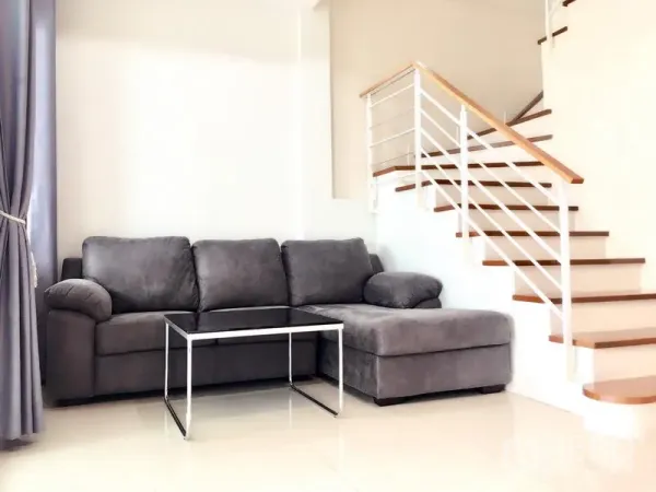 ทาวน์เฮาส์ ให้เช่าในPrawet, Bangkok - ห้องนั่งเล่นสว่างพร้อมโซฟาแอลสีเทา ข้างบันไดไม้.