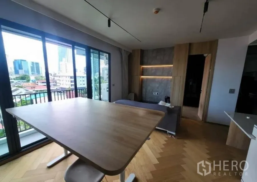 公寓 出租或出售在Phaya Thai, Bangkok - 客厅面向推拉落地门通往阳台，可见城市景观与内置层架。