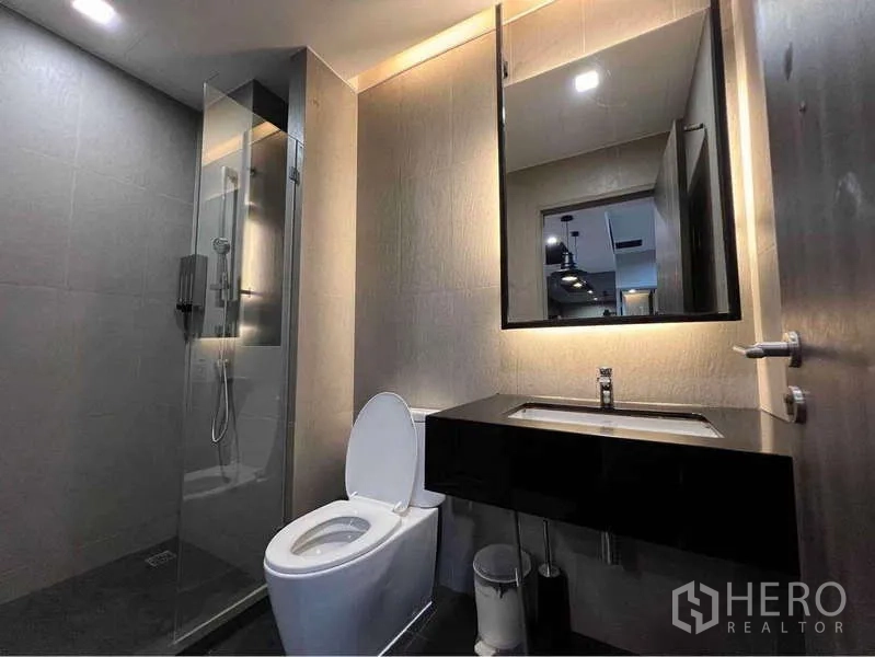 Condominium for rent - Contemporary bathroom with glass shower enclosure, backlit mirror and dark vanity.