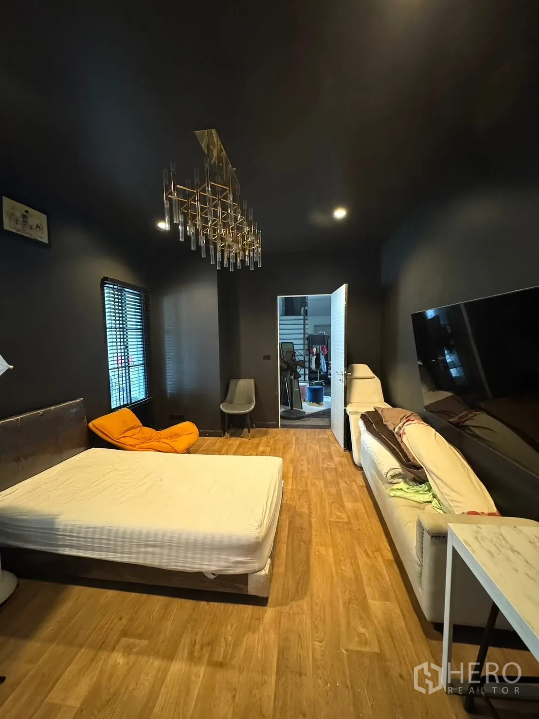 独立式住宅 出售在Mueang Pathum Thani, Pathum Thani - 深色主题卧室，吊灯、沙发与电视墙。