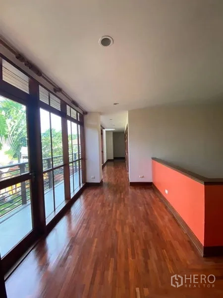 บ้าน ให้เช่าในSuan Luang, Bangkok - โถงชั้นบนพื้นไม้พร้อมผนังกระจกเต็มบานและทางออกสู่ระเบียง