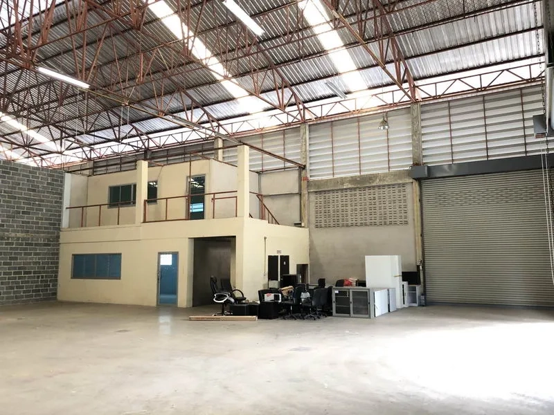 货栈 出租在Khlong Sam Wa, Bangkok - 内部视角，挑高空间，二层办公室盒体与大型卷闸门，混凝土地面。