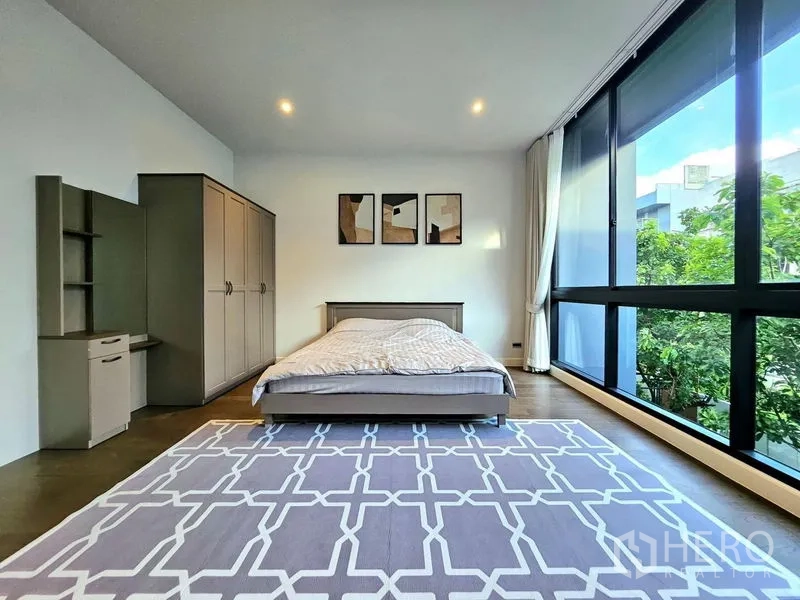 Detached House for rent in Bang Kapi, Bangkok - Corner bedroom with wall‑to‑wall windows overlooking greenery and large rug