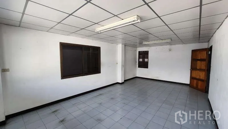 Warehouse for rent in Nong Khaem, Bangkok - Upper office area from another angle showing multiple windows, tiled floor, and fluorescent lighting.