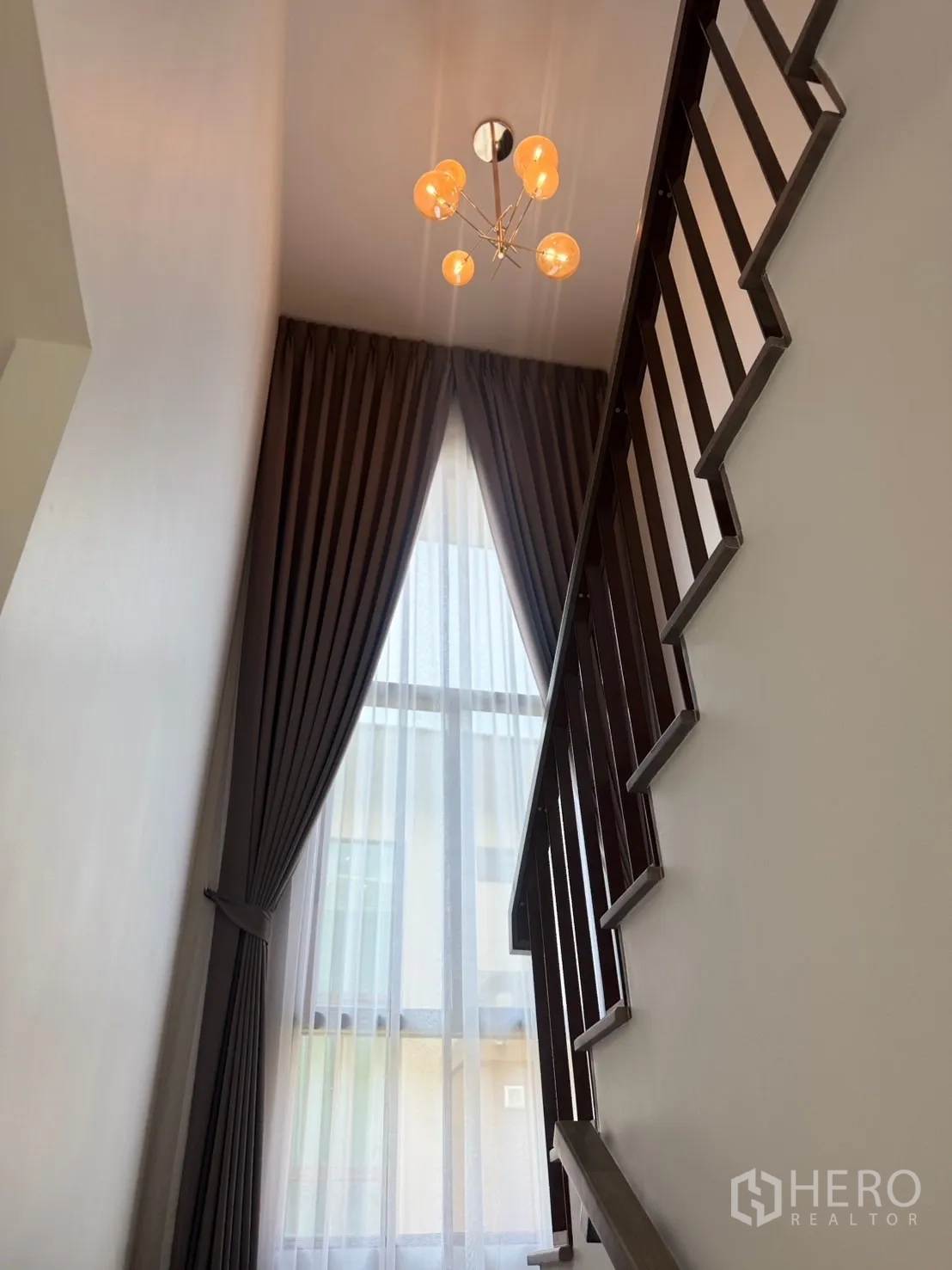 บ้าน ให้เช่าหรือขายในBang Kapi, Bangkok - บันไดบ้านกับช่องแสงสูง ม่านโปร่ง และโคมไฟสไตล์ร่วมสมัย