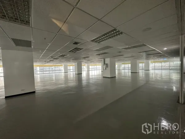 สำนักงาน ให้เช่า - ออฟฟิศว่างเปล่าขนาดใหญ่ เพดานกริดพร้อมไฟ และกระจกโดยรอบรับแสงธรรมชาติ.
