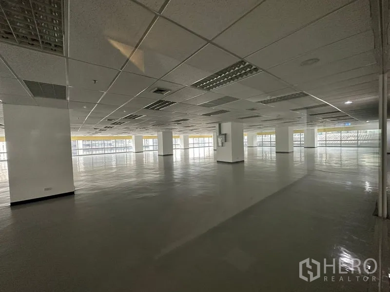 สำนักงาน ให้เช่า - ออฟฟิศว่างเปล่าขนาดใหญ่ เพดานกริดพร้อมไฟ และกระจกโดยรอบรับแสงธรรมชาติ.