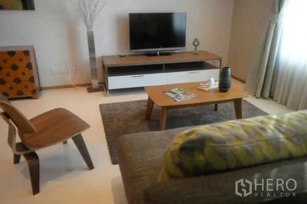 公寓 出租或出售在Khlong Toei, Bangkok - 舒适起居区，电视柜、茶几与地毯，旁有落地窗帘。